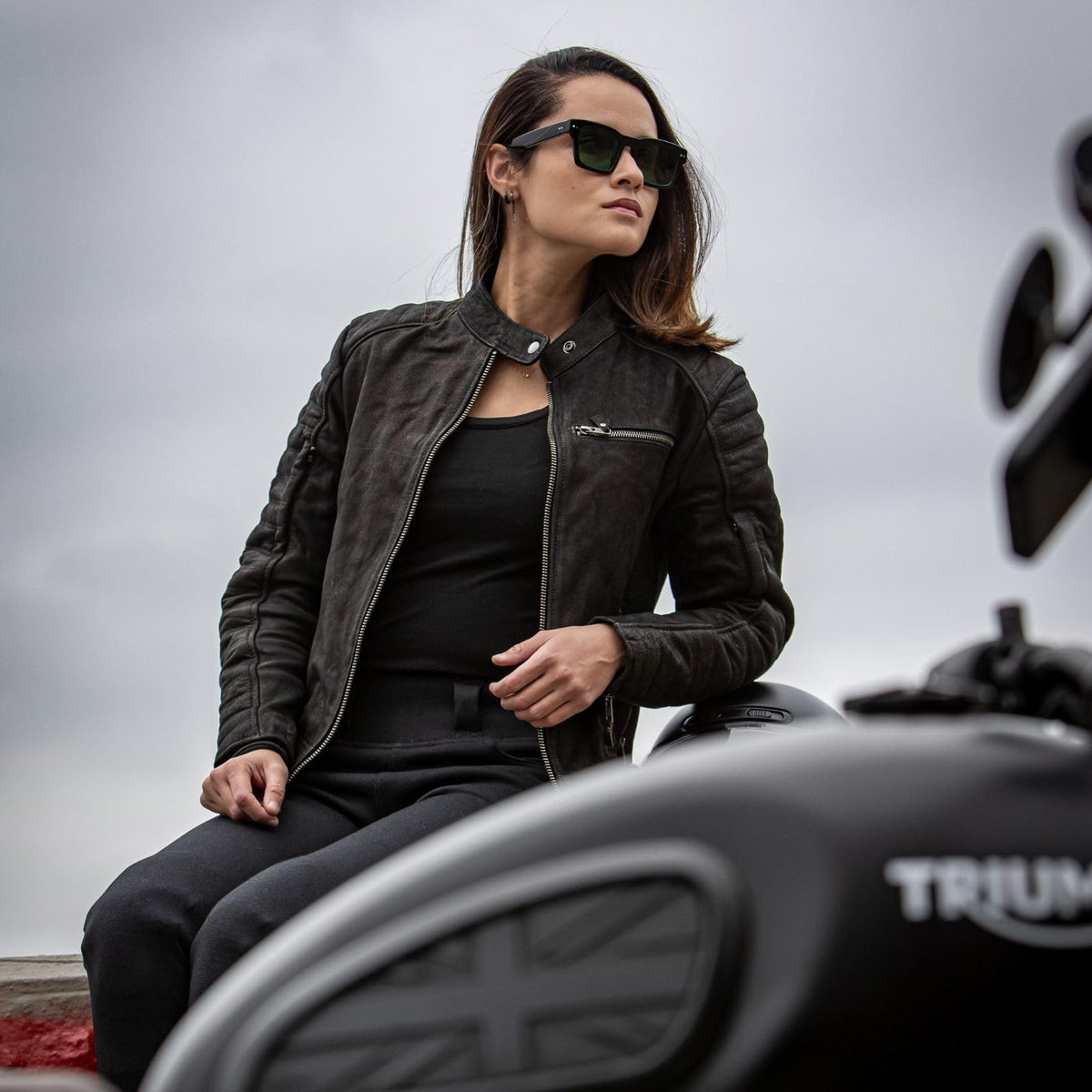 Women’s matte black leather riding jacket with stretch panels and protective armor designed for cruiser and touring motorcycles.