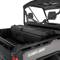 Large, low-profile black toolbox mounted across the front of a Can-Am Defender cargo bed directly behind the cab.
