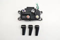 Black electrical junction box with four color-coded terminal posts, multiple mounting tabs, a green connector, and three protective rubber terminal covers.